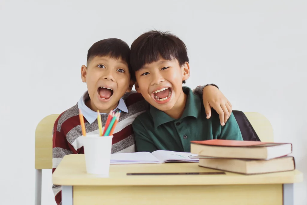 two smiling children behind a desk