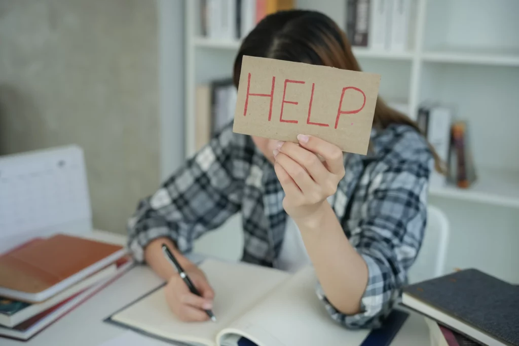 a student taking exam holding a note that says help in all caps